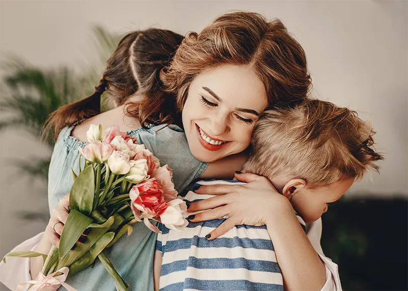 mother hugging daughter and son with a bouquet of tulips